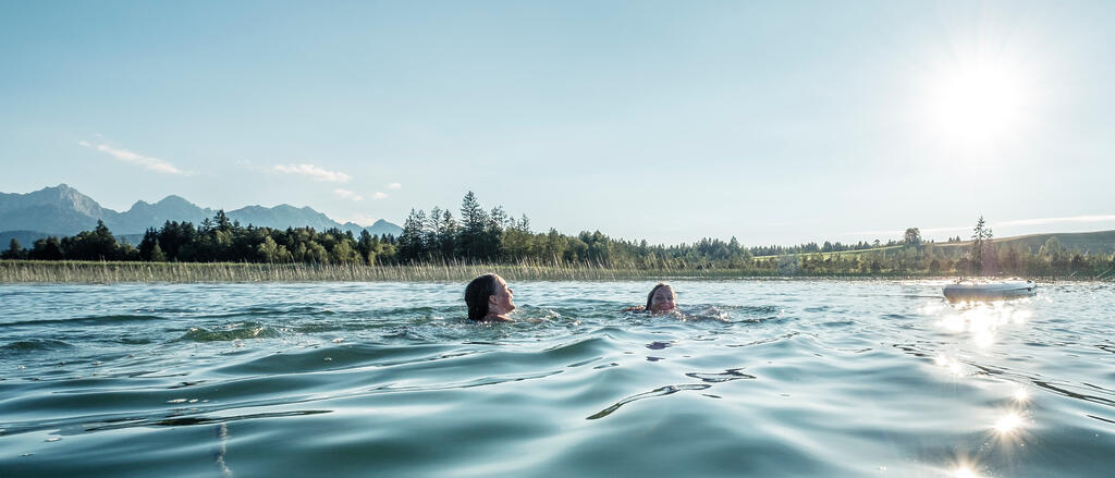 Zwei Mädchen schwimmen in einem Allgäuer Badesee