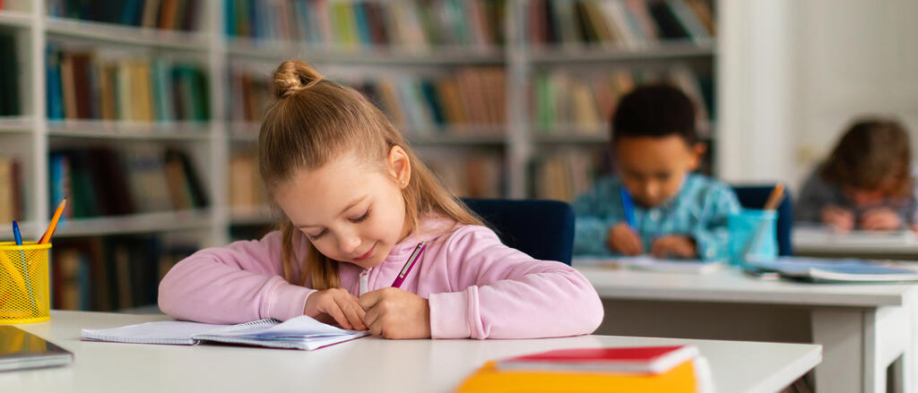 Ein Mädchen sitzt im Klassenzimmer und übt das Schreiben