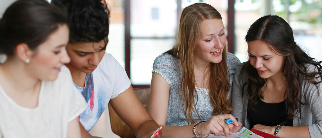 Junge Schülerinnen und Schüler beschäftigen sich in Gruppenarbeit mit inhaltlichen Fragen ihres Fachunterrichts.