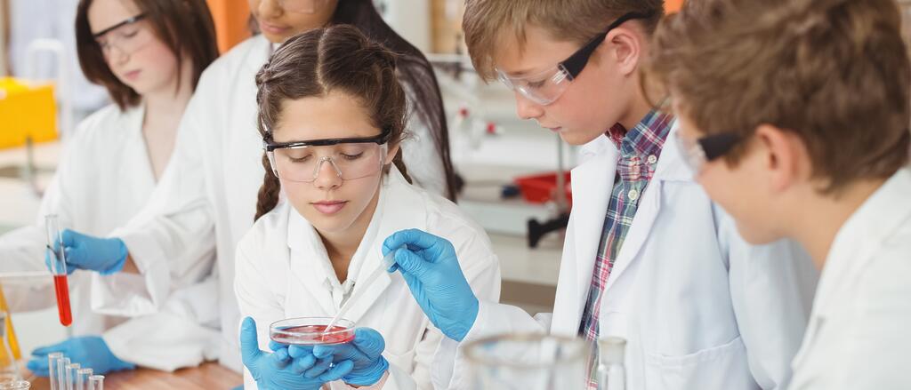 Schülerinnen und Schüler in Labormänteln nehmen Proben.
