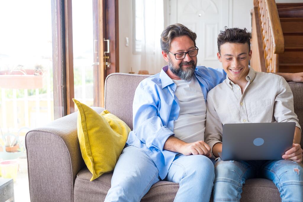 Vater und Sohn sitzen vor Laptop