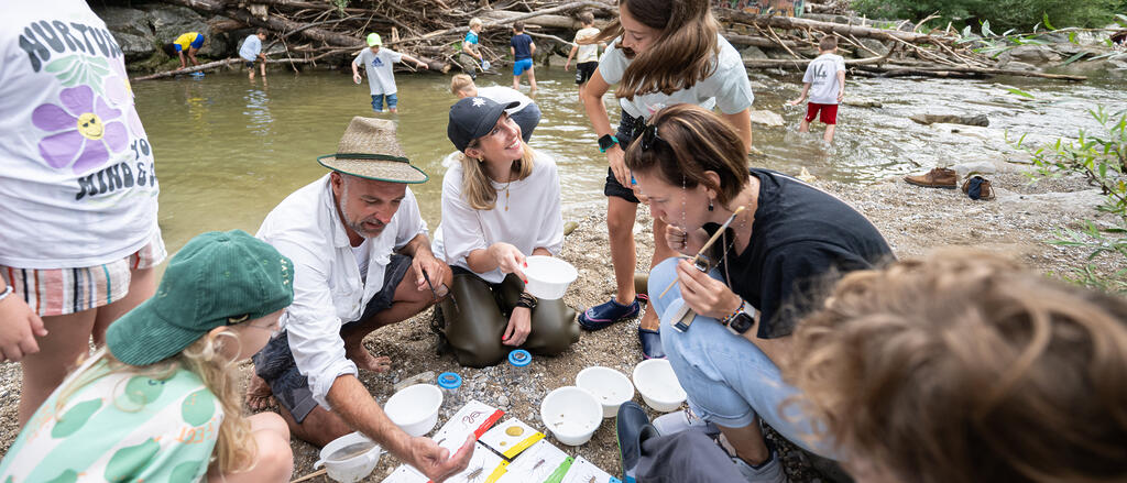 Kultusministerin Anna Stolz (Mitte) und Fischerpräsident Axel Bartelt (3. v. l.) erforschen mit Viertklässlerinnen und Viertklässlern die Unterwasserwelt der Isar