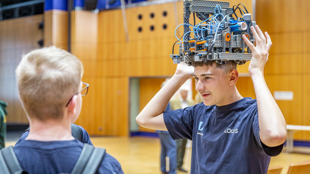 Zwei Jungen sind auf dem Bild zu sehen, der rechte im Bild trägt einen Robotikhelm