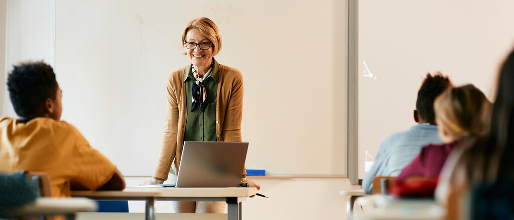 Lehrerin am Pult vor einer Schulklasse