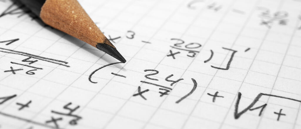 Blatt mit mathematischen Gleichungen und darüber ein Bleistift
