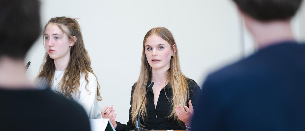 Zwei Mädchen und zwei Jungen stehen am Rednerpult und debattieren 